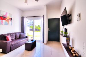 uma sala de estar com um sofá e uma televisão em Jaco Modern & Beach Apartment - Lapa Living A1 em Jacó