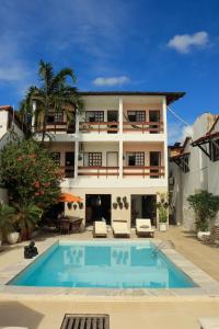 a house with a swimming pool in front of a building at Pousada Praiana in Pipa