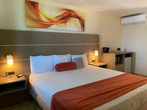 Habitación de hotel con cama grande y almohada roja en Hotel El Guajataca, en Quebradillas