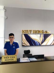 a man standing behind a desk with a sign at Kiet Hong Hotel in Rach Gia