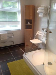 y baño con bañera, silla y lavamanos. en Clay Farm Guest House en Bromley