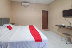um quarto com uma cama branca com uma fita vermelha em RedDoorz @ Waena Jayapura em Sentani