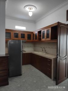 cocina con armarios de madera y nevera de acero inoxidable en Kelana 1 Luxury Homestay Semarang, 3 bedrooms, en Semarang