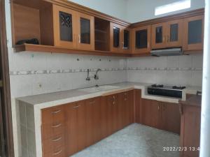 a kitchen with wooden cabinets and a sink at Kelana 1 Luxury Homestay Semarang, 3 bedrooms in Semarang