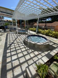 a patio with a hot tub under a white pergola at DiRoma Fiori Caldas Novas - YMT - 323 in Caldas Novas