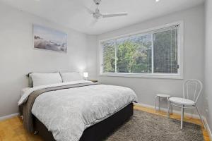 a bedroom with a bed and a window and a chair at Watonga Waves in Port Macquarie