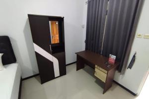 a bedroom with a bed and a desk and a window at RedDoorz Syariah near Alun Alun Purwokerto 2 in Purwokerto