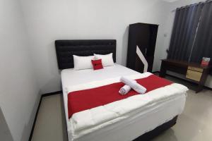 a bedroom with a large bed with white and red sheets at RedDoorz Syariah near Alun Alun Purwokerto 2 in Purwokerto