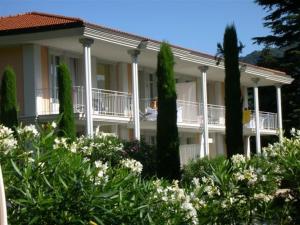 a large white building with trees in front of it at Residence Ville Lago Lugano in Porto Ceresio
