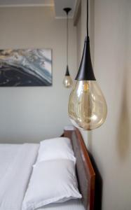 una lámpara colgada sobre una cama con sábanas blancas en Agnantio Hotel & Spa en Sidhirókastron
