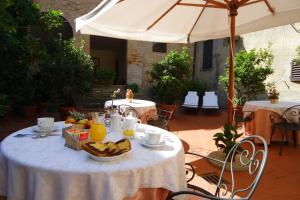 a table with a bowl of fruit and an umbrella at Hotel L'Antico Pozzo in San Gimignano