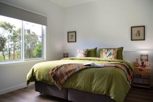 ein Schlafzimmer mit einem Bett mit einer grünen Bettdecke und einem Fenster in der Unterkunft Acacia House in Eganstown