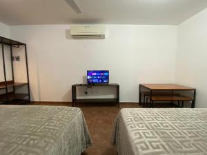 a room with two beds and a television and a table at CASA ROMEL in Ciudad Valles