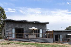 a black house with a deck and an umbrella at Banksia Villa in Eganstown
