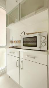 a kitchen with white cabinets and a microwave at Apartamento con piscina y WIFI a 100 metros de la playa en Somo in Somo +11 photos