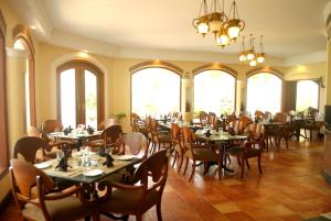 una sala da pranzo con tavoli, sedie e finestre di The Hans Coco Palms a Puri