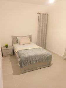 ein weißes Schlafzimmer mit einem Bett und einem Fenster in der Unterkunft Cosy Apartment in Ebene in Quatre Bornes