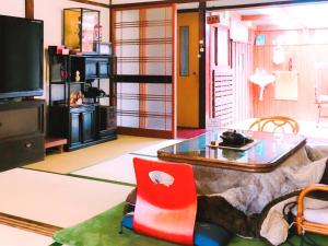 a living room with a glass table and a red chair at Guest House Kominka Nagomi in Izumi-Sano