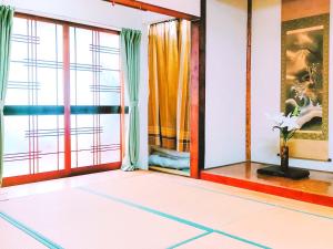 een kamer met een witte vloer en ramen bij Guest House Kominka Nagomi in Izumi-Sano
