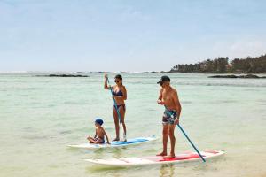 a group of people standing on surfboards in the ocean at C Mauritius in Belle Mare
