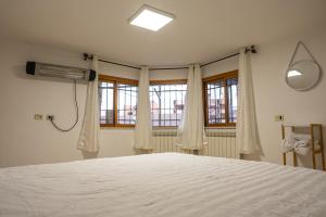 een slaapkamer met een wit bed en 2 ramen bij Kings of Hermon - Electric Vehicles Friendly! in Majdal Shams