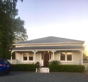 une maison blanche avec une voiture garée devant elle dans l'établissement La Rocque Cottage, à Martinborough