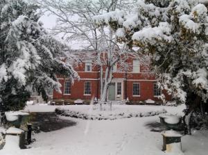 a red brick building with snow covered trees and benches at Breedon Hall in Derby