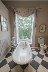 a bathroom with a tub and a toilet and a window at Breedon Hall in Derby