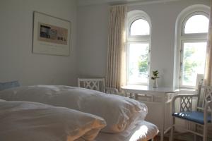 a white bedroom with a bed and two windows at Troense Bed and Breakfast by the sea in Svendborg