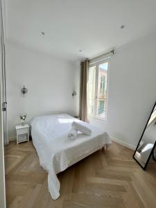 a white bedroom with a bed and a window at amazing new property in the heart of the old town of antibes in Antibes
