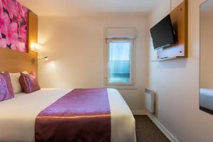 a hotel room with a bed and a window at Fasthotel Orleans Zénith in Orléans