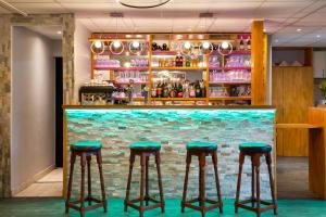 un bar avec des tabourets verts devant un mur de briques dans l'établissement Fasthotel Orleans Zénith, à Orléans