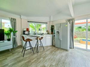 uma cozinha com um frigorífico e 2 bancos de bar em Tina's Living Paradise II - Guesthouses with private pool, 5 min to beach em Rayong
