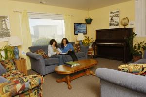 Due donne sedute in un soggiorno con pianoforte di HI Pigeon Point Lighthouse Hostel a Pescadero
