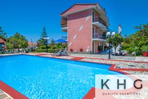 a large swimming pool in front of a pink building at Jovanna Studios in the nature with Pool! in Trapezaki
