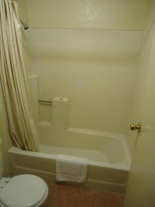 a bathroom with a toilet and a bath tub and a toilet at Economy Inn in Victorville