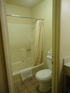 a bathroom with a white toilet and a shower at Economy Inn in Victorville