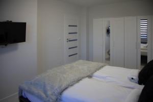 a white room with a bed and a flat screen tv at Apartament Wrocław Borowska in Wrocław