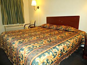 a hotel room with a bed with a colorful bedspread at Economy Inn in Victorville