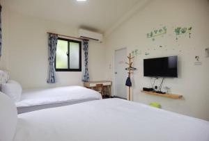a bedroom with two beds and a flat screen tv at Kinmen Huquian 58 in Jinhu