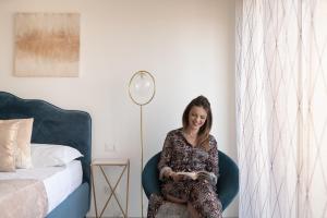 Kobieta siedząca na krześle czytająca książkę obok łóżka w obiekcie Ortigia Boutique Plaza Apt w Syrakuzach +20 zdjęć