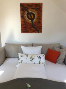 ein Sofa mit Kissen und ein Gemälde an der Wand in der Unterkunft Villa zur Schmied'n in Ehrenhausen