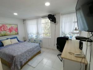a bedroom with a bed and a desk with a computer at Casa La Fe in Cartagena de Indias