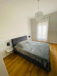 a white bedroom with a large bed and a chandelier at Le Nid Blanc Nice Centre in Nice