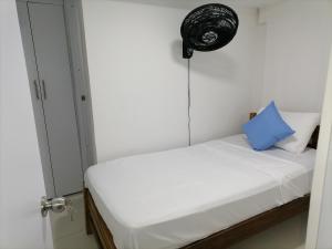 a small bedroom with a white bed with a blue pillow at Casa La Fe in Cartagena de Indias