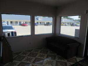 a living room with three windows and a couch at Travelers Inn and Suites Liberty in Liberty