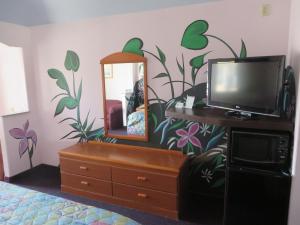 a bedroom with a dresser and a tv and a mirror at Travelers Inn and Suites Liberty in Liberty