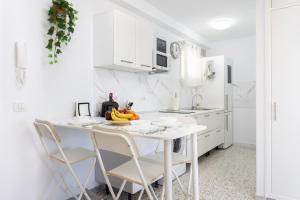 eine weiße Küche mit einem weißen Tisch und Stühlen in der Unterkunft Home2Book Apartamento Vista al Mar in Bajamar