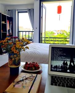 laptopa na biurku z talerzem owoców w obiekcie hoi an center town w Hoi An