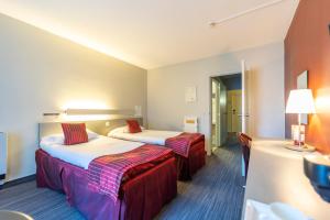 Cette chambre comprend 2 lits et une table. dans l'établissement Hotel Ambiotel, à Tongres